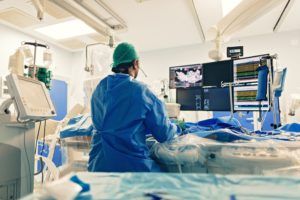 Surgeon in operating room standing over patient with a fluoroscope and performing minimally invasive spine surgery
